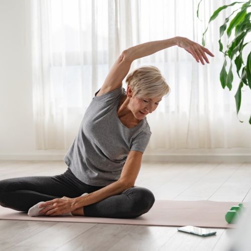 Femme âgée s'étirant sur un tapis exercices physiques ménopause