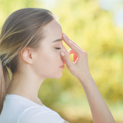 jeune femme se tenant le front avec les yeux fermés