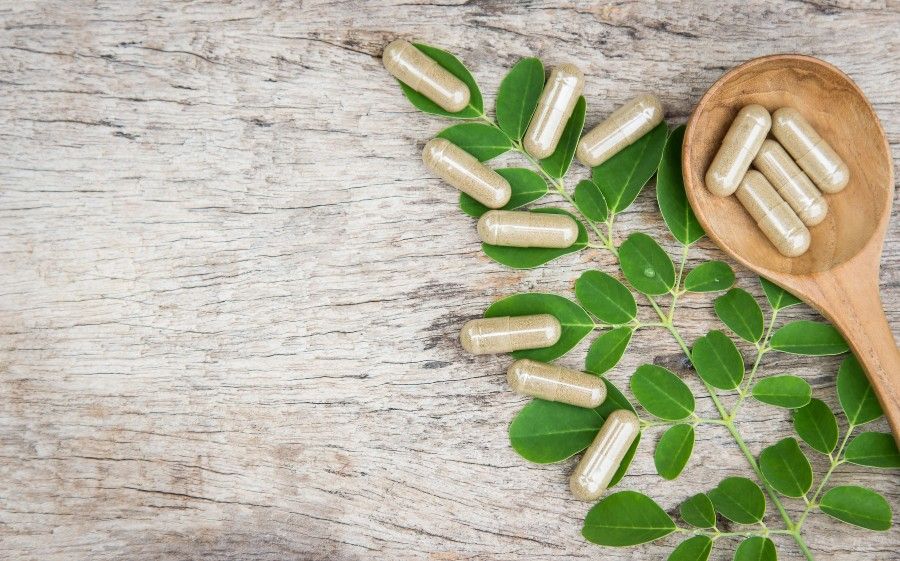 gélules dans une cuillère en bois avec des feuilles vertes Traitements naturels ménopause