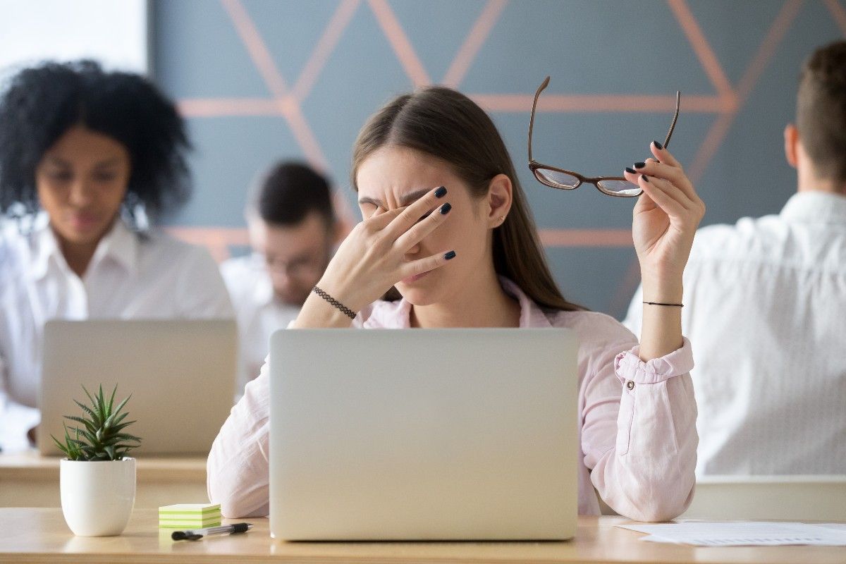 femme devant un ordinateur se frottant les yeux à cause d'une Fatigue visuelle et stress