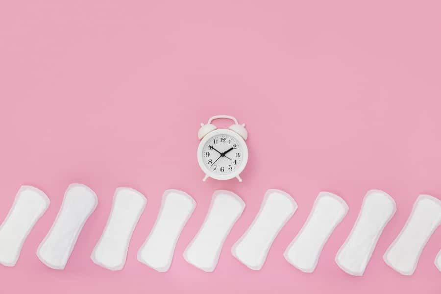 serviettes hygiéniques devant un réveil pour illustrer les Saignements à la ménopause