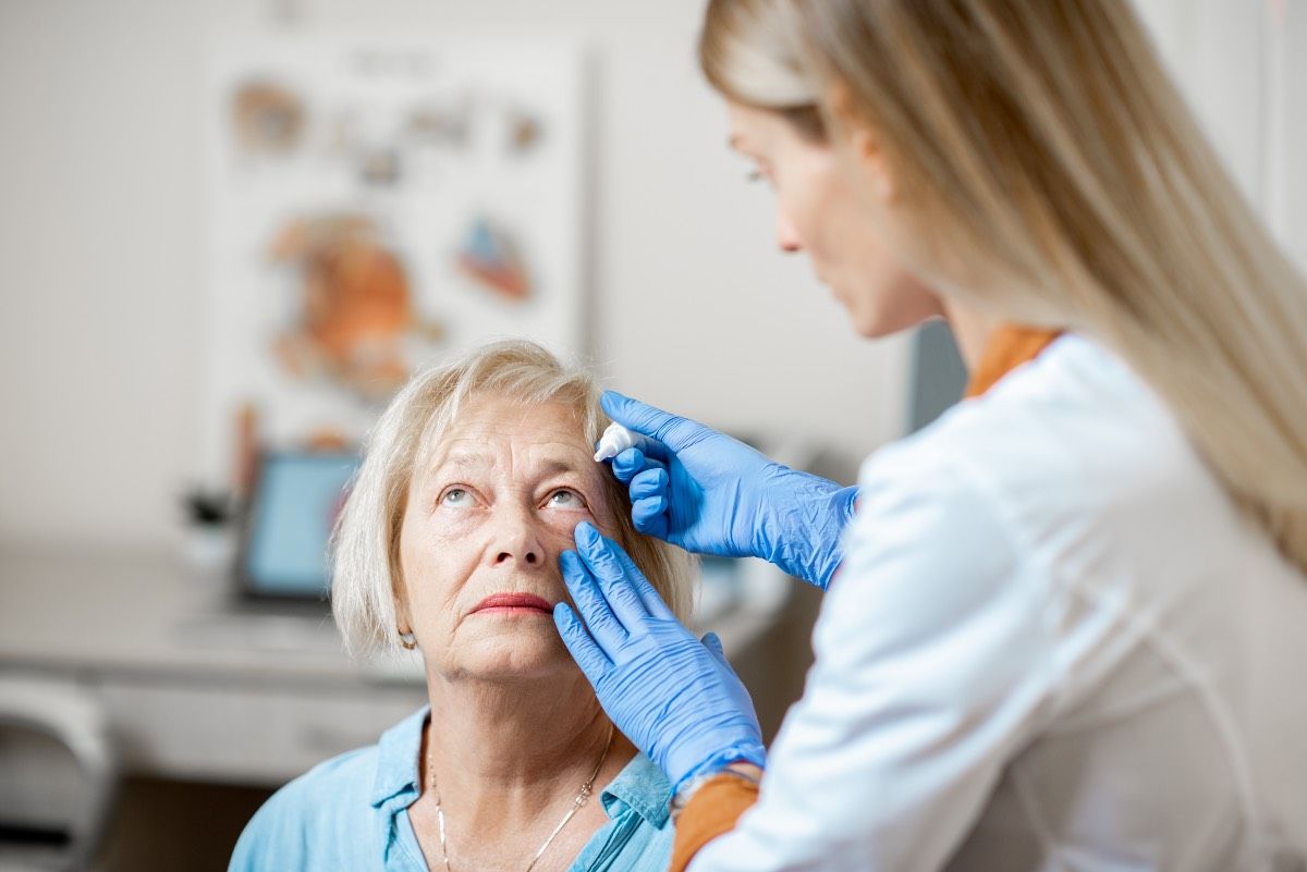 Une femme medecin verse des gouttes sur un patient age