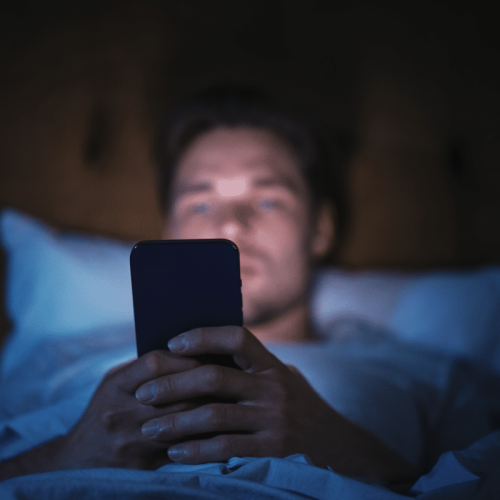 Homme qui utilise son téléphone portable dans son lit la nuit