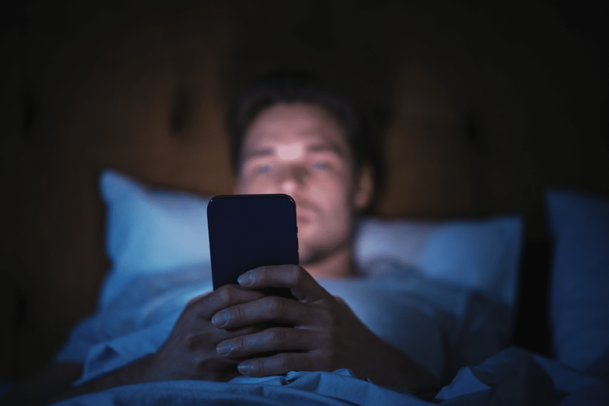 Homme qui utilise son téléphone portable dans son lit la nuit