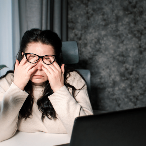 Femme travaillant à la maison assise avec un ordinateur portable frottant les yeux fatigués